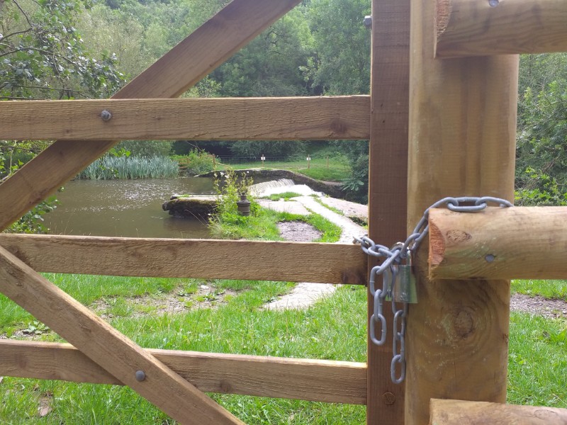 A chained and padlocked access gate in the new fencing sealing off access to the weir in the Monsal valley